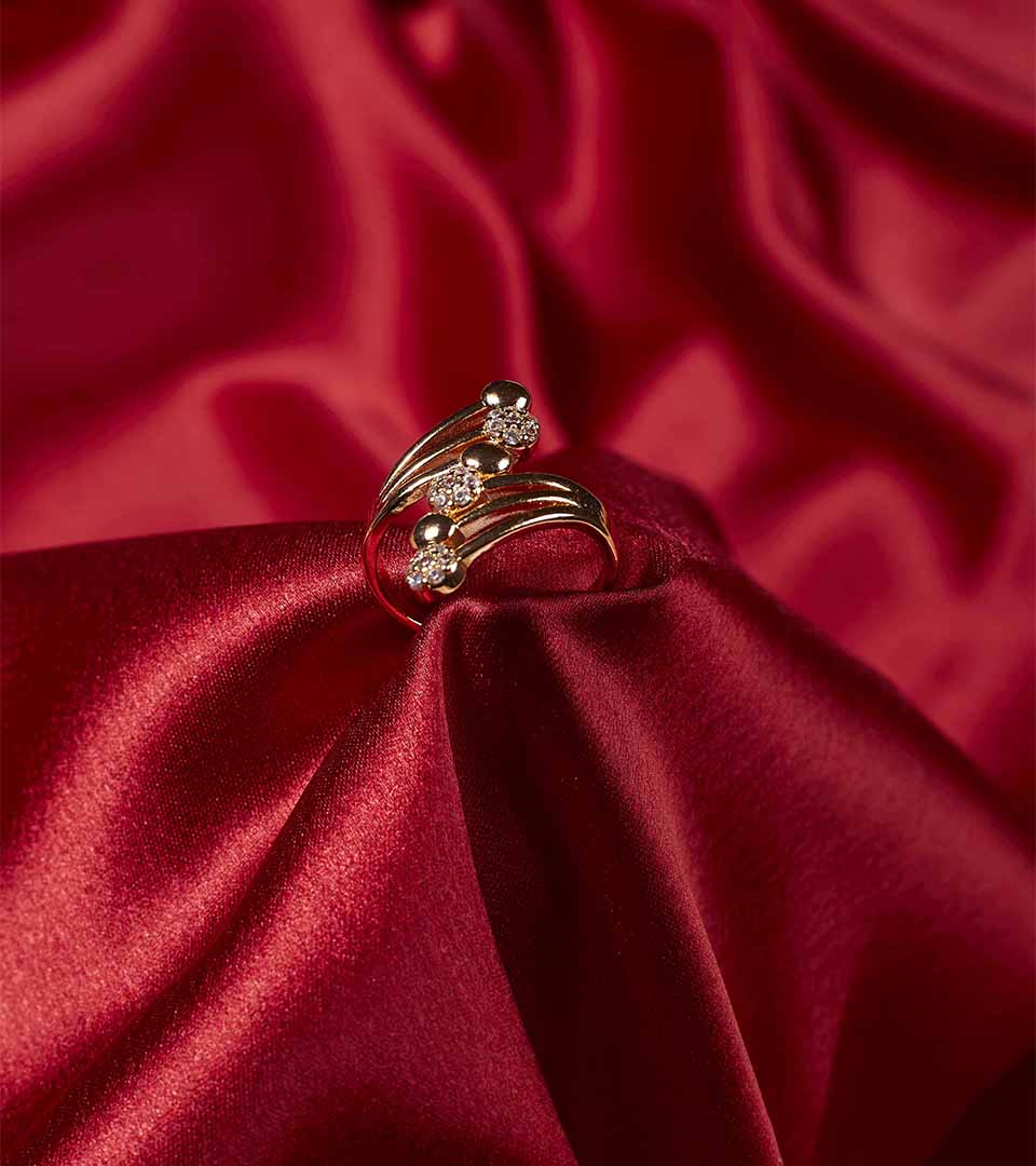 Golden Sculptural Swirl Ring on red satin fabric